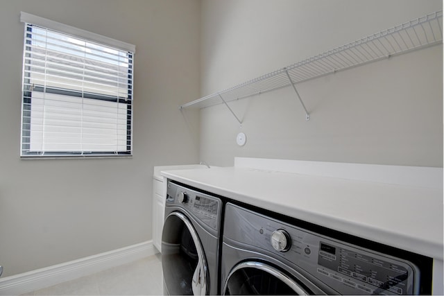 clothes washing area featuring washer and clothes dryer and light tile patterned floors