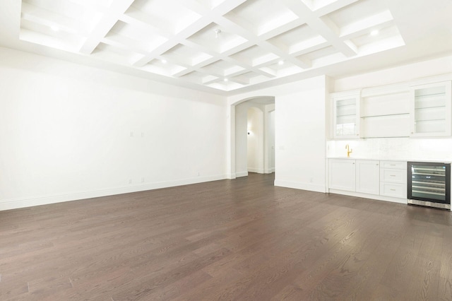 unfurnished living room with dark wood-type flooring, coffered ceiling, beverage cooler, and beamed ceiling