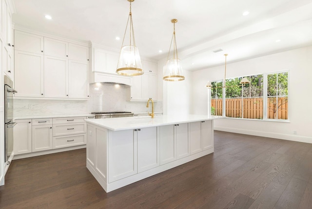 kitchen featuring pendant lighting, dark hardwood / wood-style flooring, white cabinets, and a center island with sink