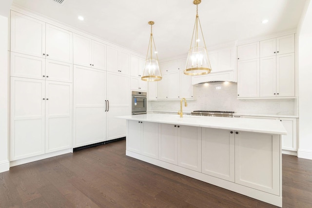 kitchen featuring white cabinetry, hanging light fixtures, appliances with stainless steel finishes, and a center island with sink