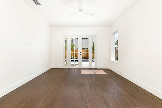 empty room featuring french doors, ceiling fan, a healthy amount of sunlight, and dark hardwood / wood-style flooring