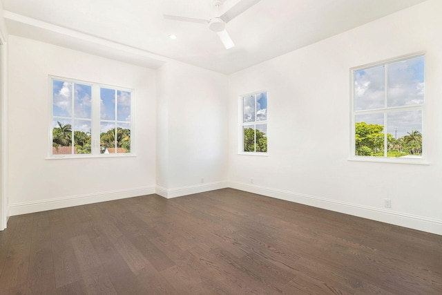 empty room with ceiling fan, a healthy amount of sunlight, and dark hardwood / wood-style flooring