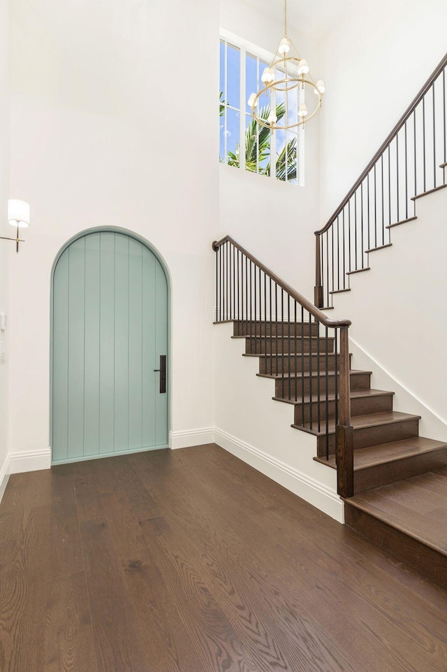 foyer with a towering ceiling, dark hardwood / wood-style floors, and a chandelier