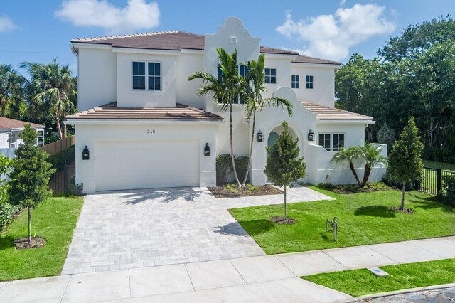 mediterranean / spanish-style home featuring a garage and a front lawn