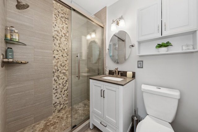 bathroom featuring vanity, a shower with shower door, and toilet