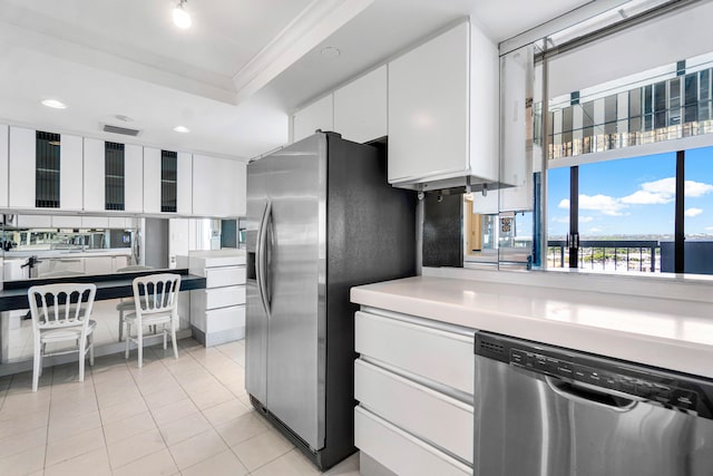 kitchen featuring ornamental molding, a tray ceiling, white cabinetry, and stainless steel appliances