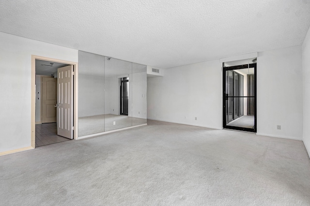 carpeted spare room with a textured ceiling