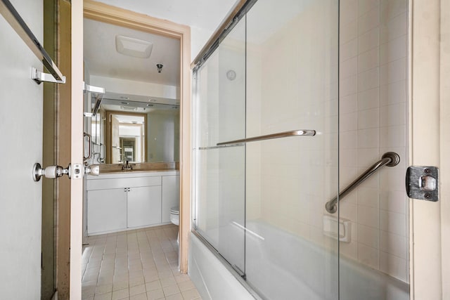 full bathroom featuring tile patterned flooring, bath / shower combo with glass door, toilet, and vanity