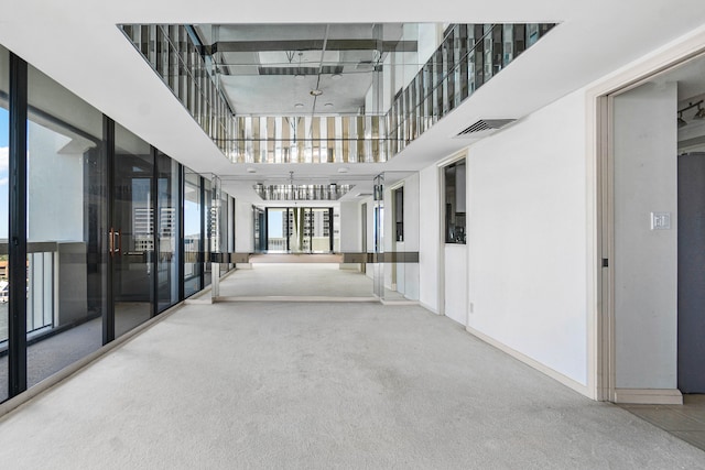 hallway featuring carpet flooring and a towering ceiling