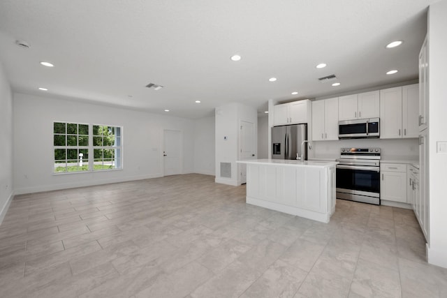 kitchen with white cabinets, light tile patterned floors, a kitchen island with sink, and stainless steel appliances