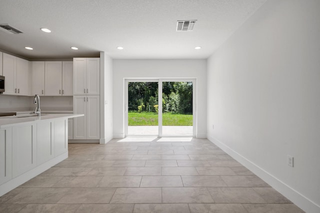 kitchen featuring a textured ceiling, light tile patterned flooring, and white cabinets