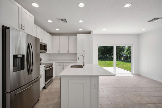 kitchen featuring a kitchen island with sink, white cabinets, light tile patterned floors, sink, and stainless steel appliances