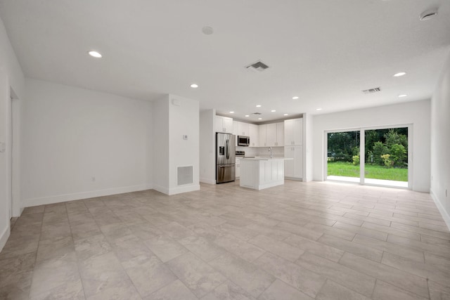 unfurnished living room with sink and light tile patterned floors