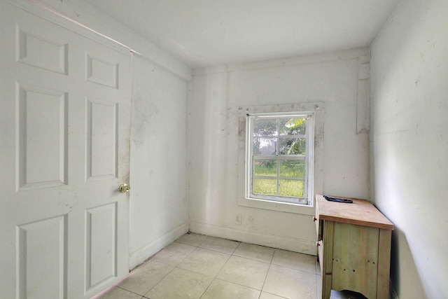 empty room with baseboards and light tile patterned flooring