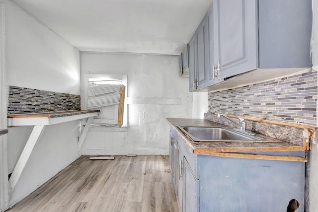 kitchen featuring light wood finished floors, a sink, and tasteful backsplash