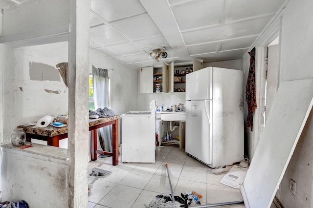 kitchen with washer / dryer, freestanding refrigerator, and light tile patterned flooring