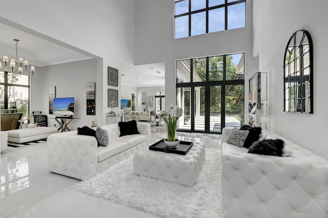 living room featuring a chandelier, a high ceiling, tile patterned floors, and a healthy amount of sunlight