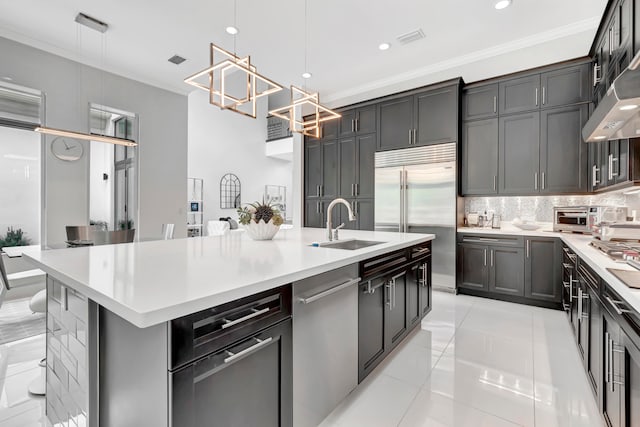 kitchen with decorative light fixtures, light tile patterned flooring, crown molding, and an island with sink