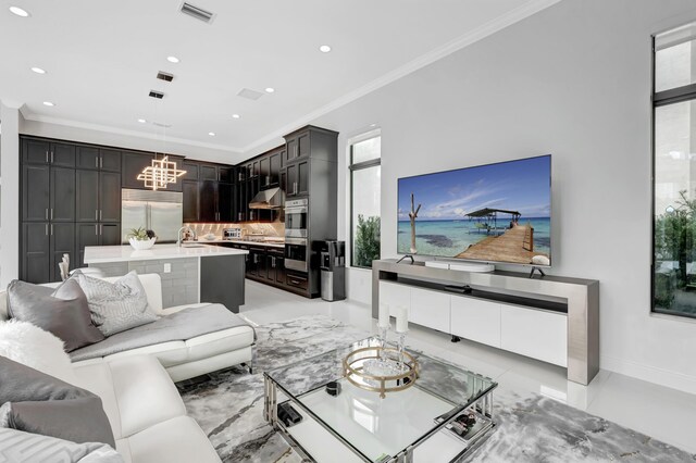 tiled living room featuring ornamental molding, sink, and a notable chandelier