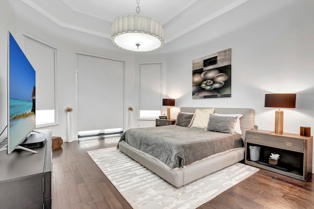 bedroom with a tray ceiling, dark hardwood / wood-style flooring, and ornamental molding