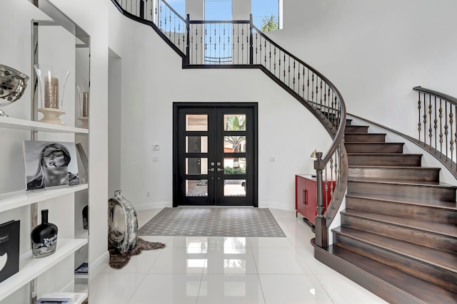 tiled entryway featuring french doors and a towering ceiling