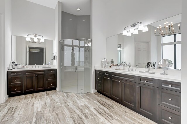 bathroom with a shower with door, a chandelier, and dual bowl vanity