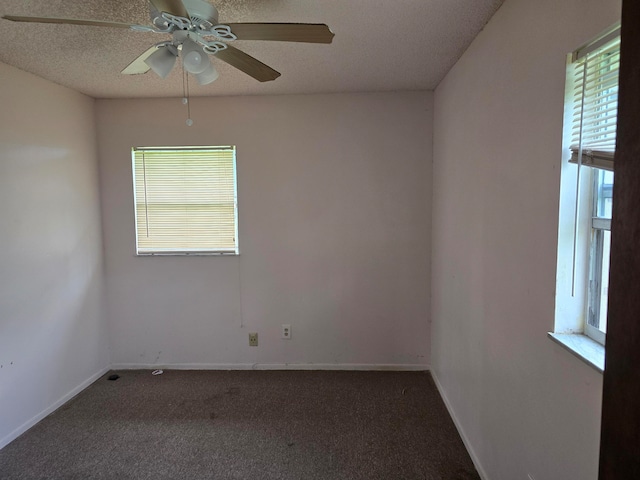 empty room with a textured ceiling, dark carpet, and ceiling fan