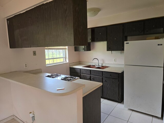 kitchen with kitchen peninsula, sink, light tile patterned floors, and white appliances