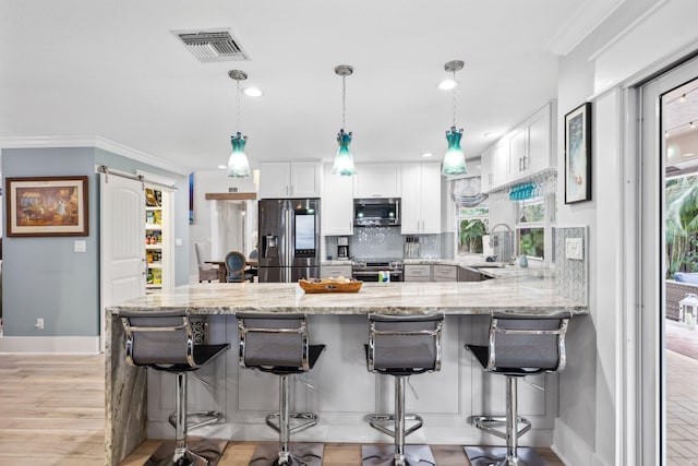 kitchen featuring a barn door, visible vents, appliances with stainless steel finishes, and white cabinets