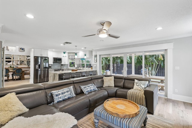 living room featuring ceiling fan, crown molding, recessed lighting, and light wood-style floors