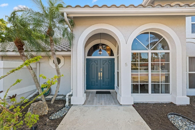 entrance to property with a tile roof and stucco siding