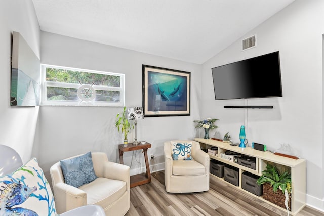 living room with lofted ceiling, baseboards, visible vents, and wood finished floors