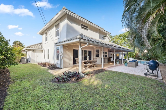 back of house featuring a tile roof, stucco siding, a lawn, an outdoor hangout area, and a patio area