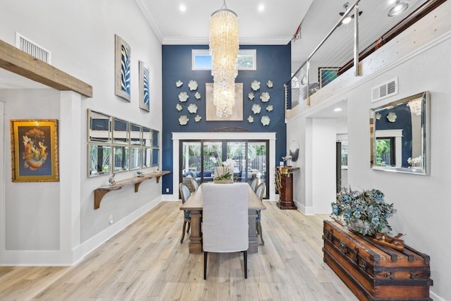 dining space featuring crown molding, visible vents, light wood-style floors, a chandelier, and baseboards