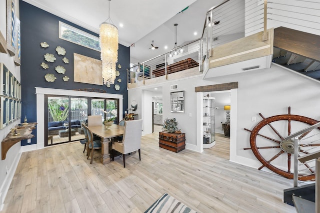 dining area with a towering ceiling, light wood-style floors, baseboards, and visible vents