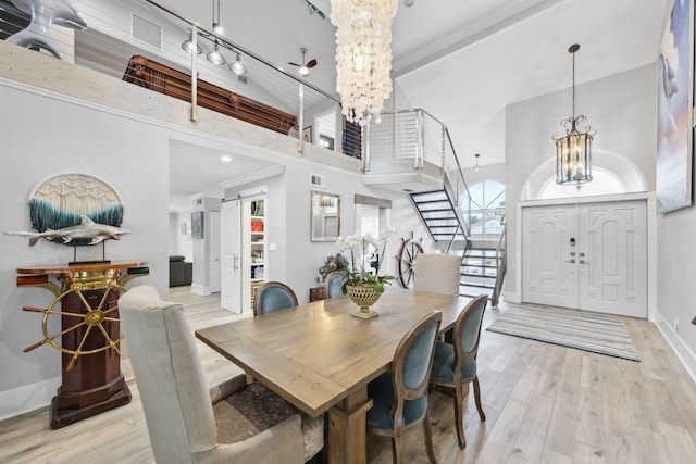 dining space with baseboards, light wood-style flooring, a high ceiling, stairs, and a notable chandelier