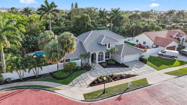 view of front of home featuring an attached garage, fence private yard, a tile roof, concrete driveway, and stucco siding