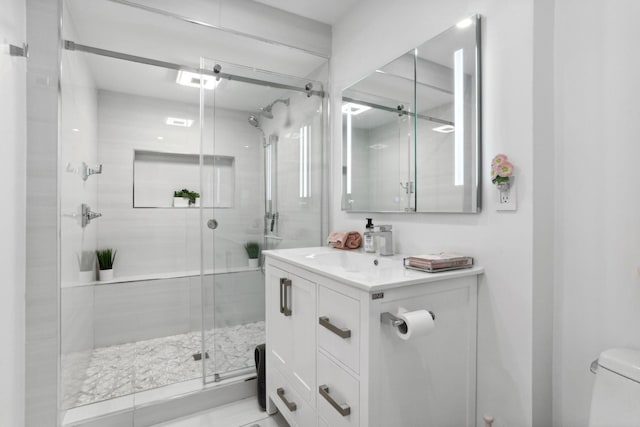 bathroom with a shower with door, vanity, and toilet