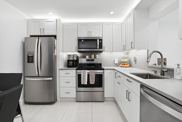 kitchen with light tile patterned floors, appliances with stainless steel finishes, sink, and white cabinets