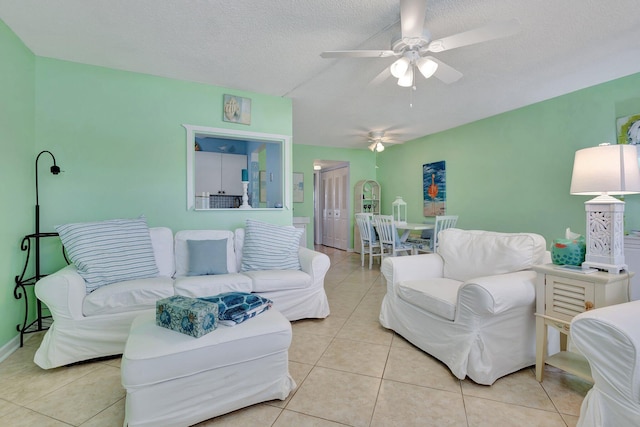 living room featuring a textured ceiling, light tile patterned floors, and ceiling fan