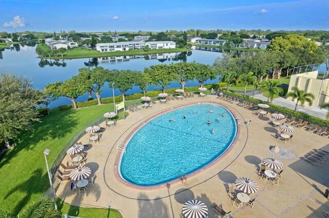 view of pool featuring a water view, a patio, and a yard