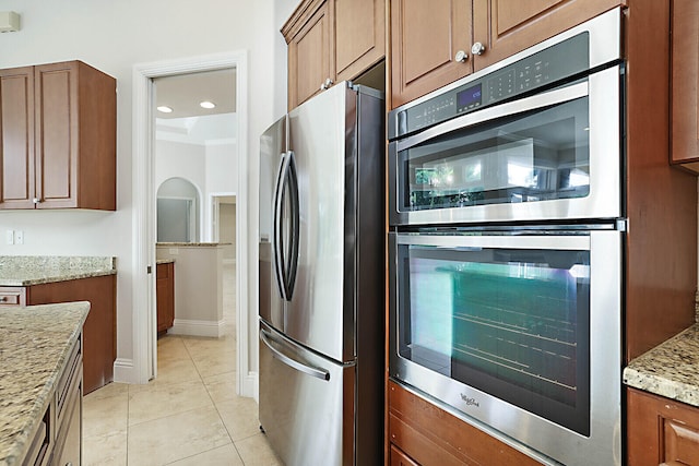 kitchen featuring light stone counters, light tile patterned floors, and appliances with stainless steel finishes