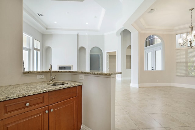 kitchen with hanging light fixtures, a raised ceiling, sink, light tile patterned floors, and light stone counters