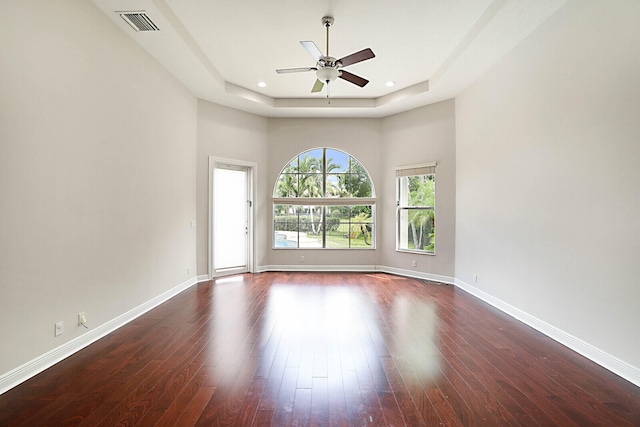 spare room featuring ceiling fan, a raised ceiling, dark wood-type flooring, and a towering ceiling