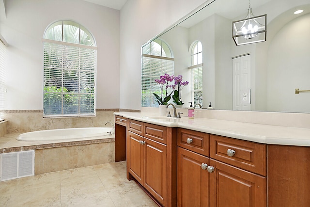 bathroom with vanity, tiled tub, and an inviting chandelier