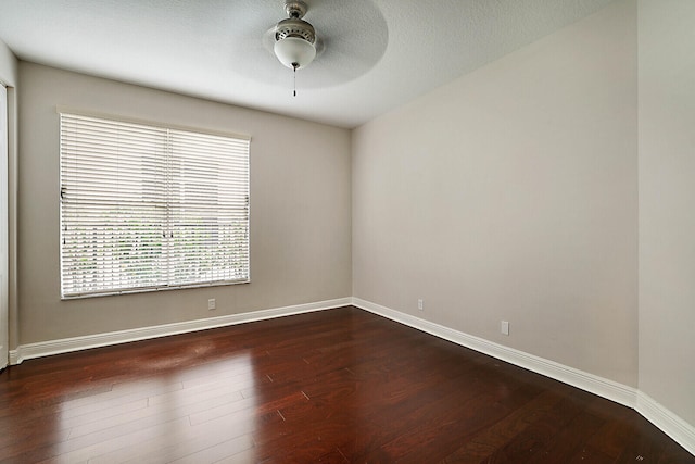 spare room with ceiling fan, a healthy amount of sunlight, and dark wood-type flooring