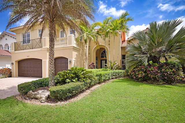 mediterranean / spanish-style house featuring a front yard, a balcony, and a garage