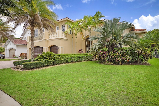 mediterranean / spanish home featuring a balcony and a front lawn