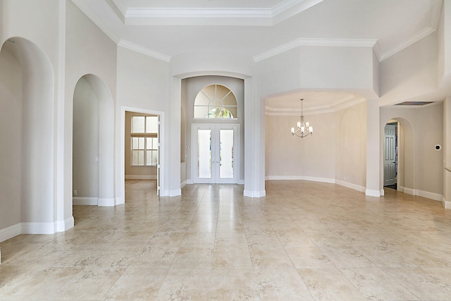 entryway with french doors, a notable chandelier, ornamental molding, and a towering ceiling