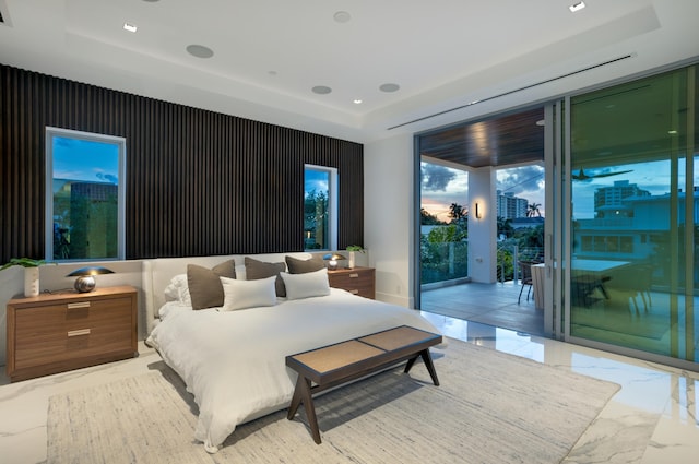 bedroom with a raised ceiling, expansive windows, and access to outside